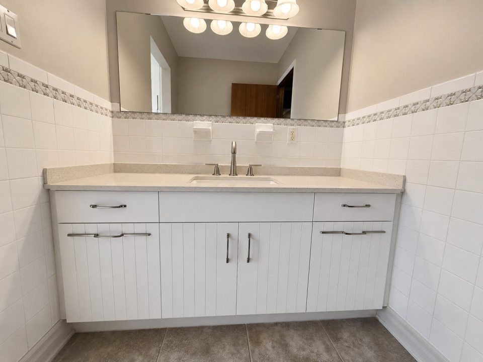 White bathroom vanity with custom profiled slab doors and accent pulls